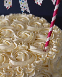 关闭在白色结霜的玫瑰盖的成品蛋糕的照片与黏附在蛋糕外面的一支串起。