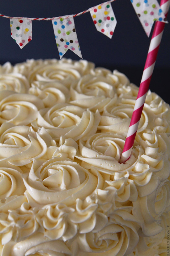 特写照片完成的蛋糕覆盖着白色糖霜玫瑰和一个命令的吸管伸出蛋糕。